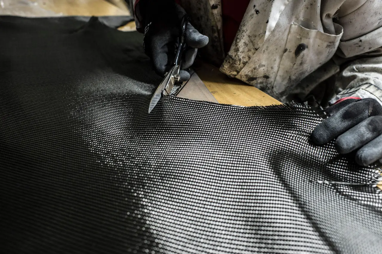 Man cuts a carbon-fiber fabric with scissors.