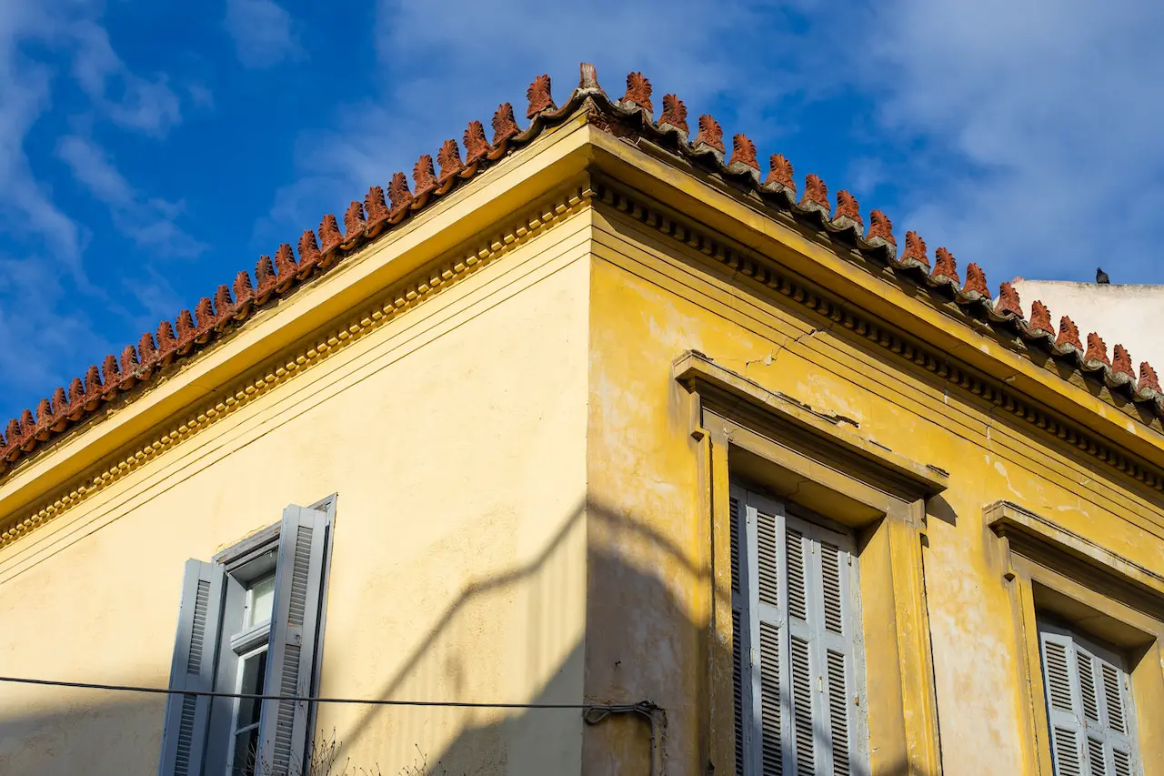 Old weathered vintage yellow house, windows with wooden shutters.