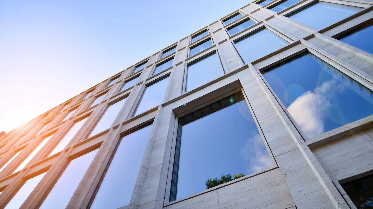 Abstract closeup of the glass-clad facade of a modern building covered in reflective plate glass.