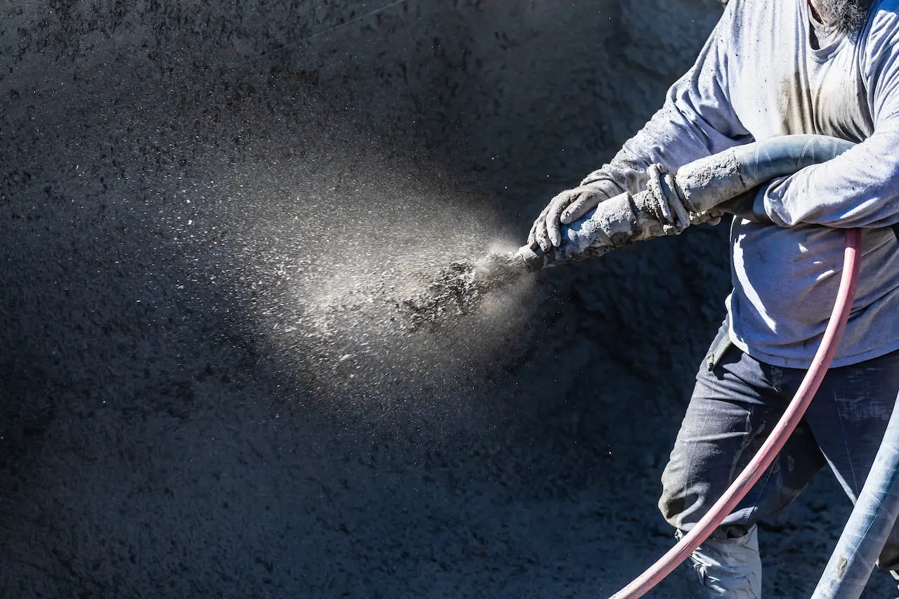 Pool Construction Worker Shooting Concrete, Shotcrete or Gunite Through Hose.